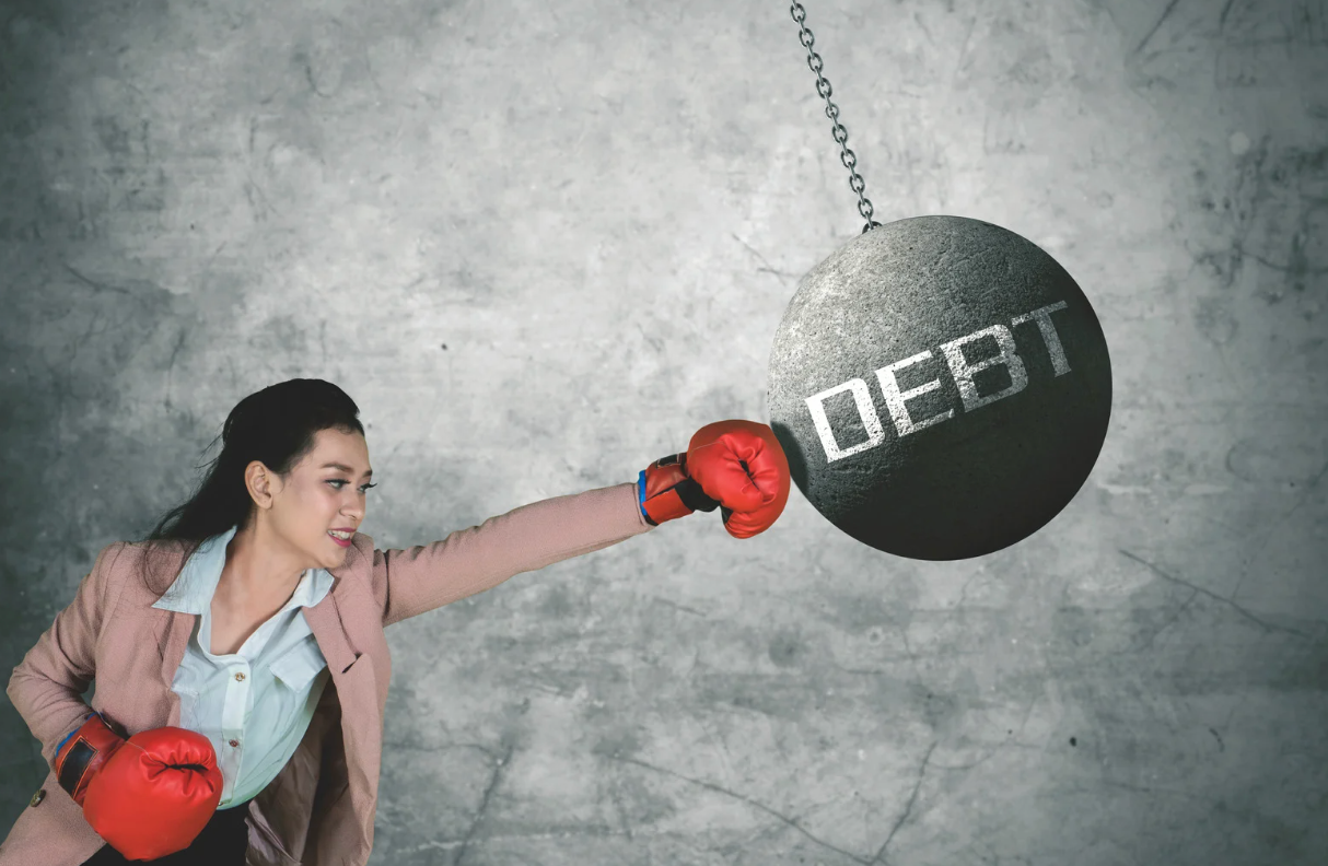 Woman in boxing gloves punching a wrecking ball labeled
