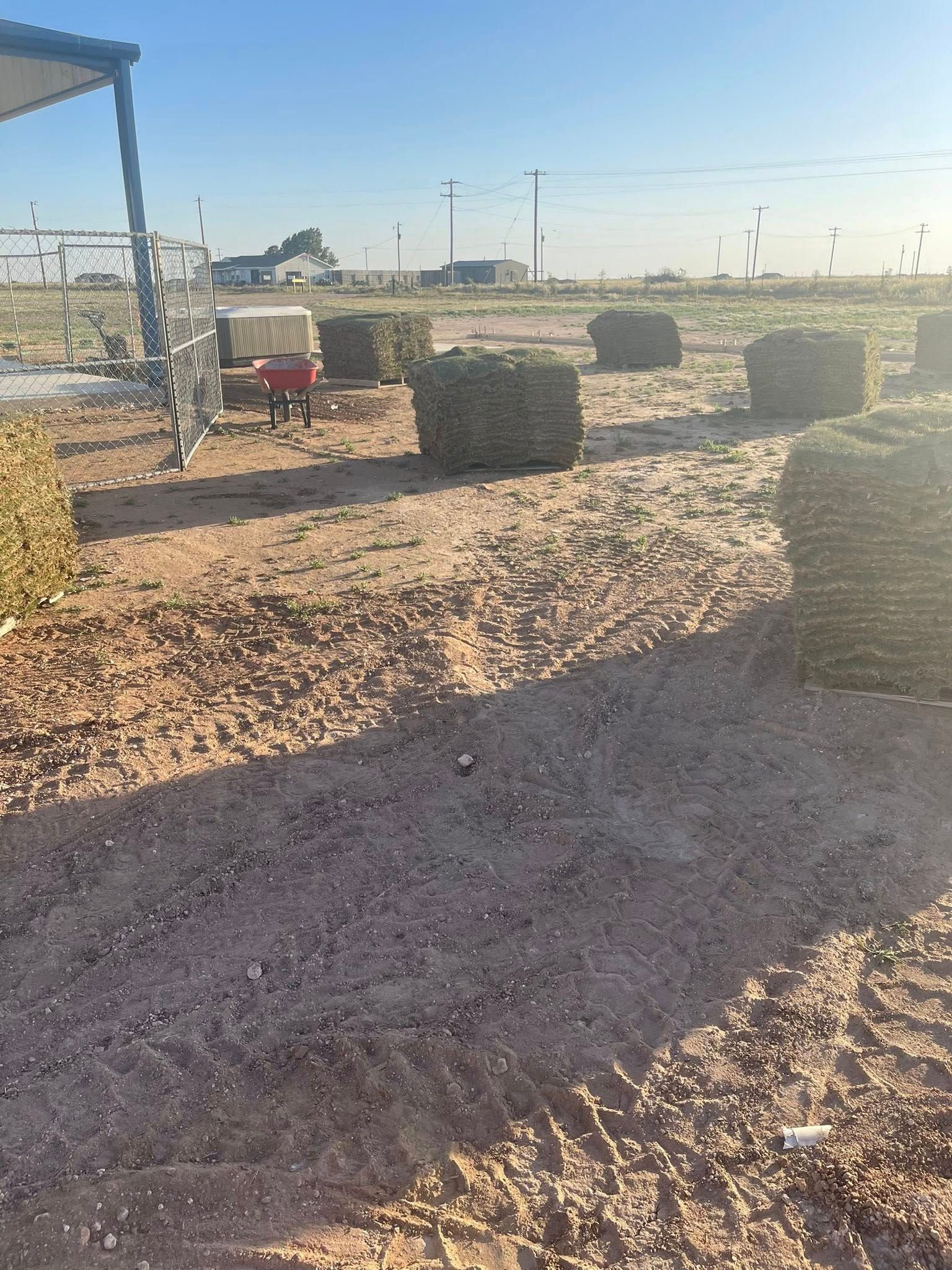 Field with square hay bales, a person nearby, and a clear sky.
