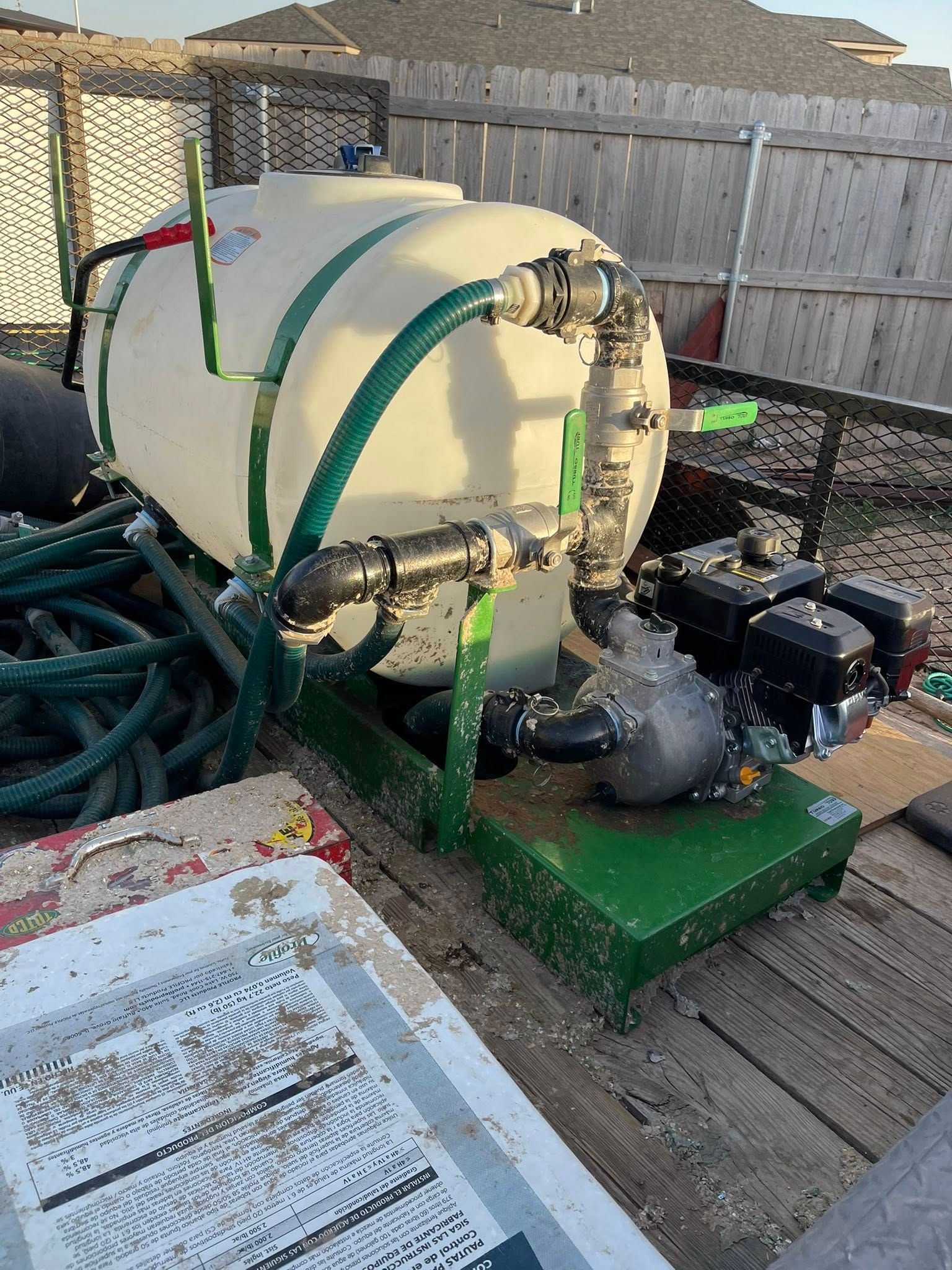White tank sprayer with green frame and hoses on a trailer.