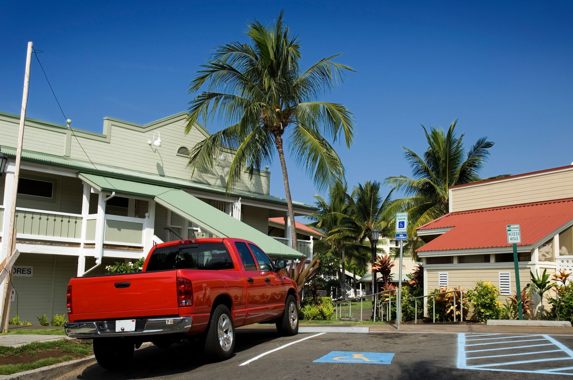 A red truck is parked in a handicapped parking spot