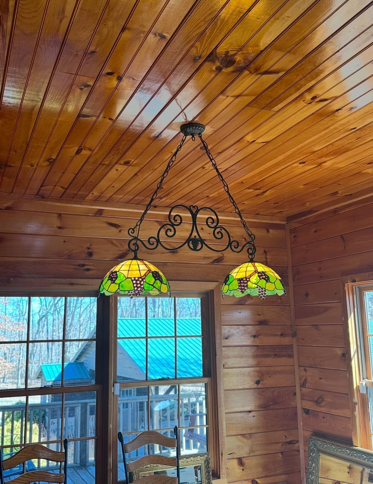Wood-paneled room with stained-glass pendant lights hanging from the ceiling near a window.