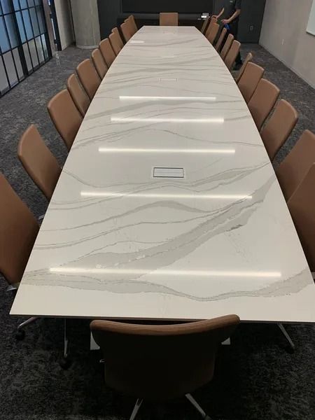 A long white table with brown chairs in a conference room.
