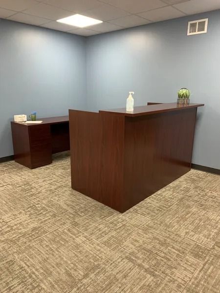 A small office with a wooden desk and a carpeted floor.