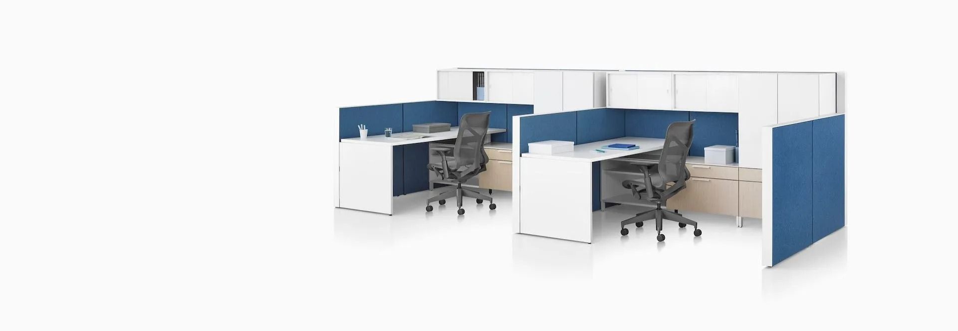 A cubicle with two desks and two chairs in an office.