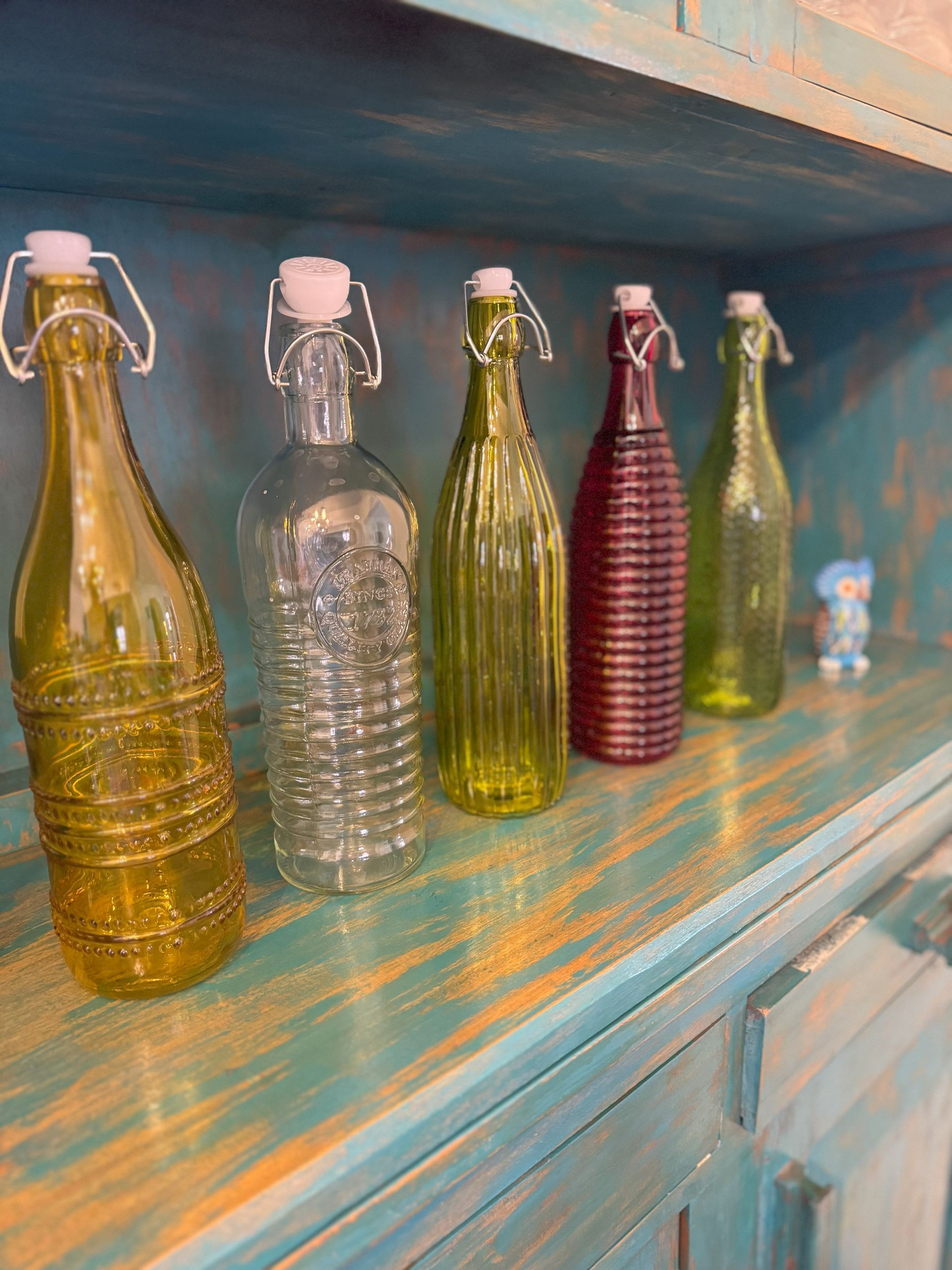 A row of colorful glass bottles are sitting on a shelf.