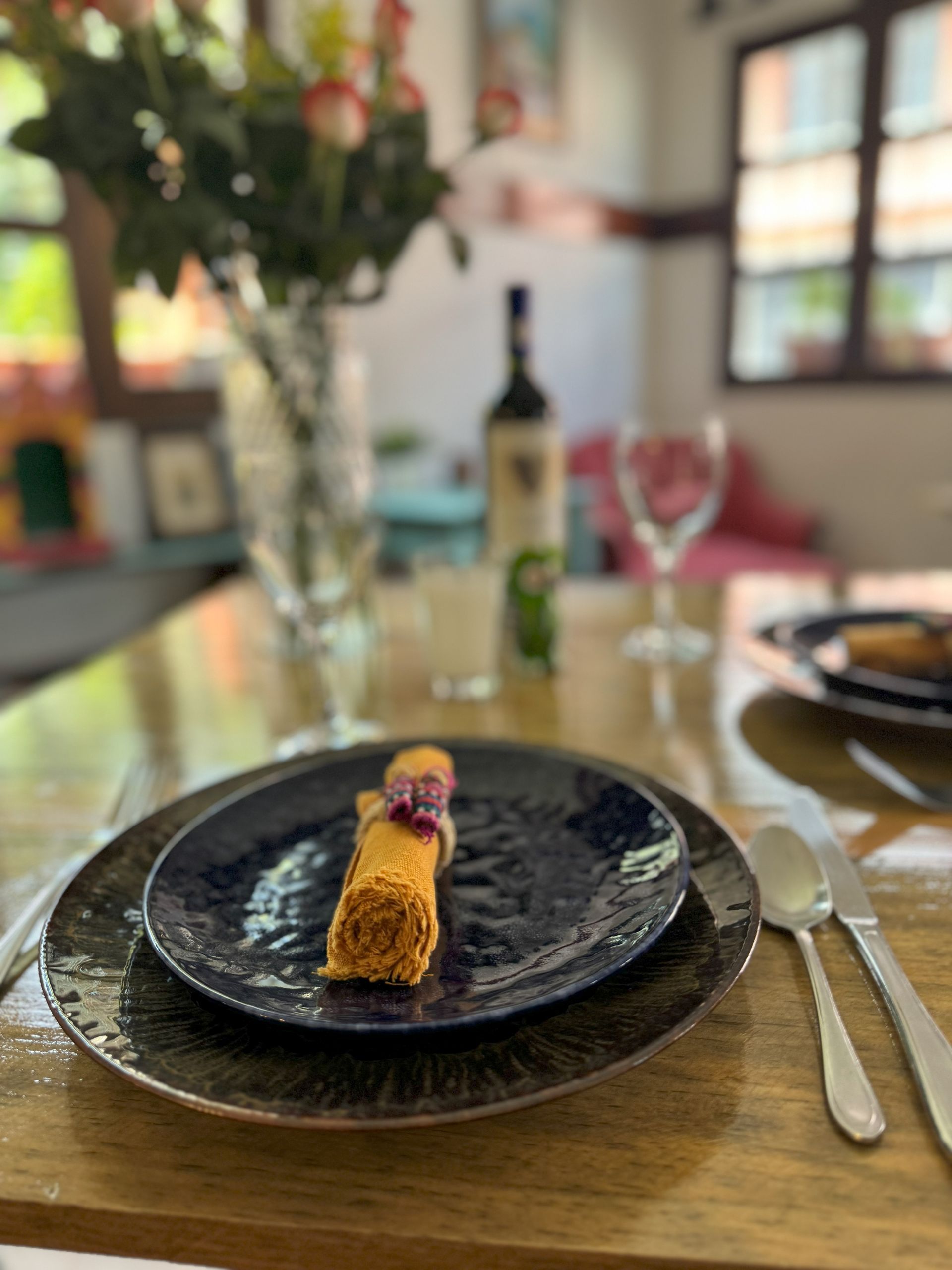 A plate of food is sitting on a wooden table next to a vase of flowers.