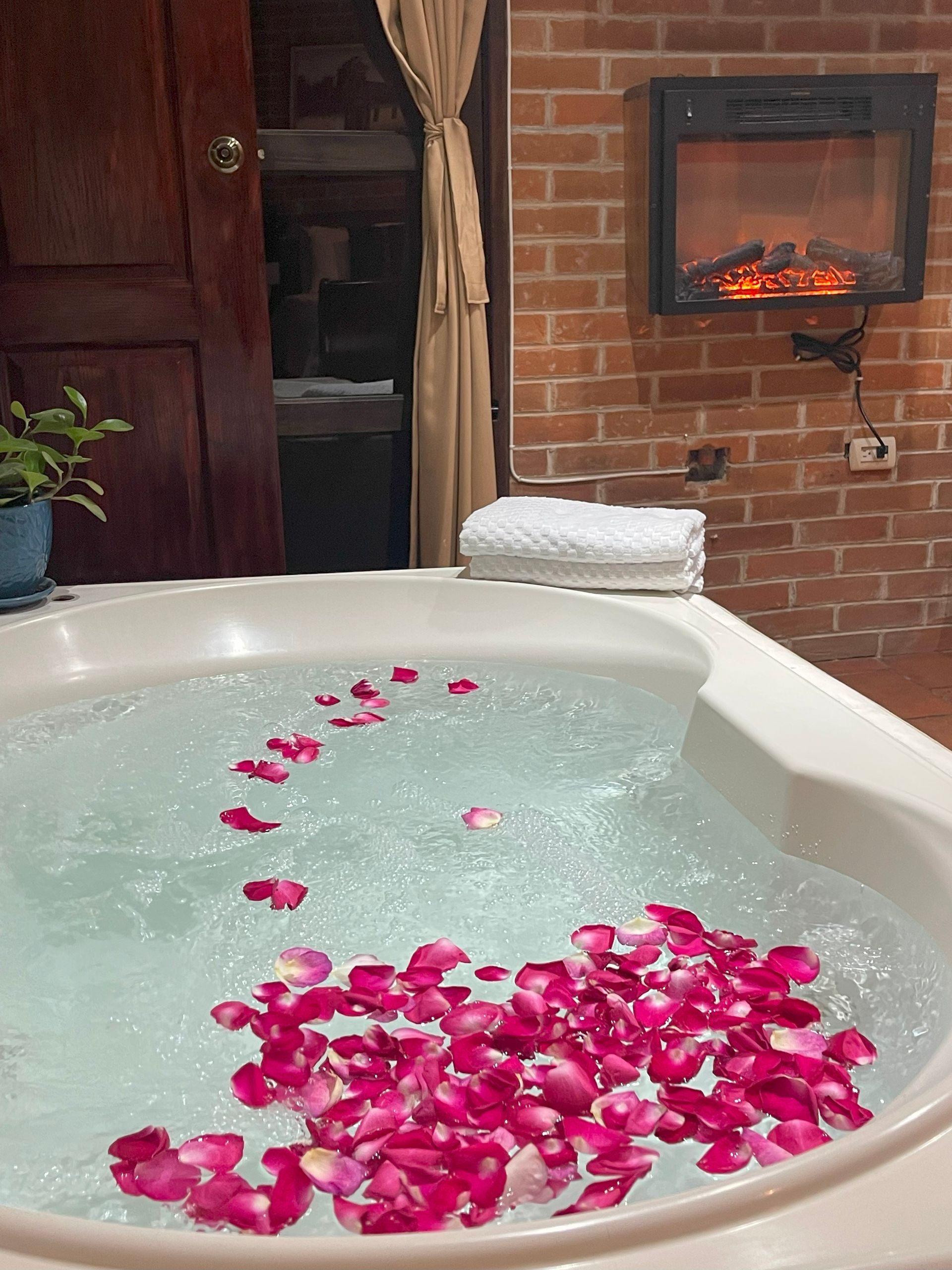 A bathtub filled with water and rose petals in a bathroom.