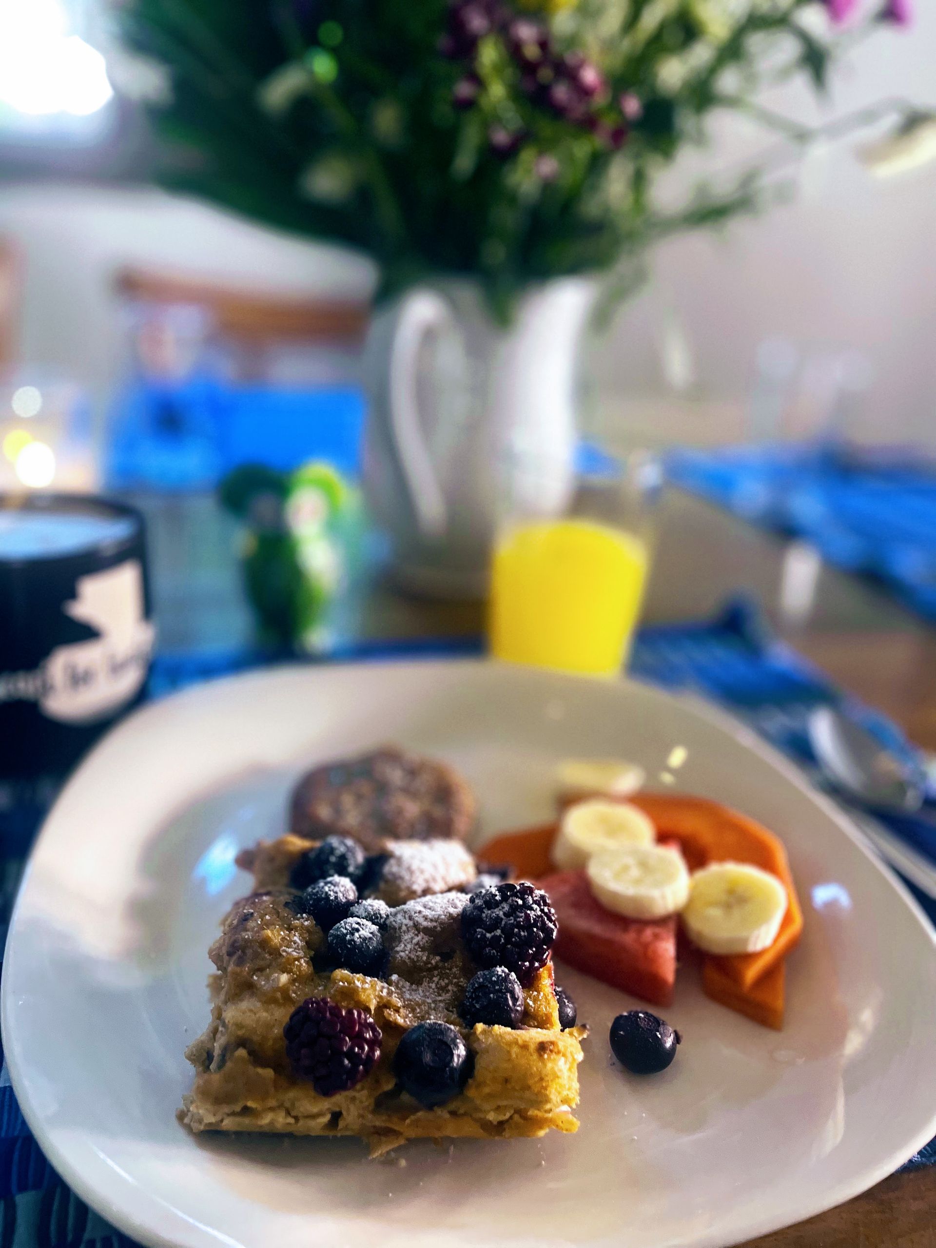 A white plate topped with french toast and fruit on a table.
