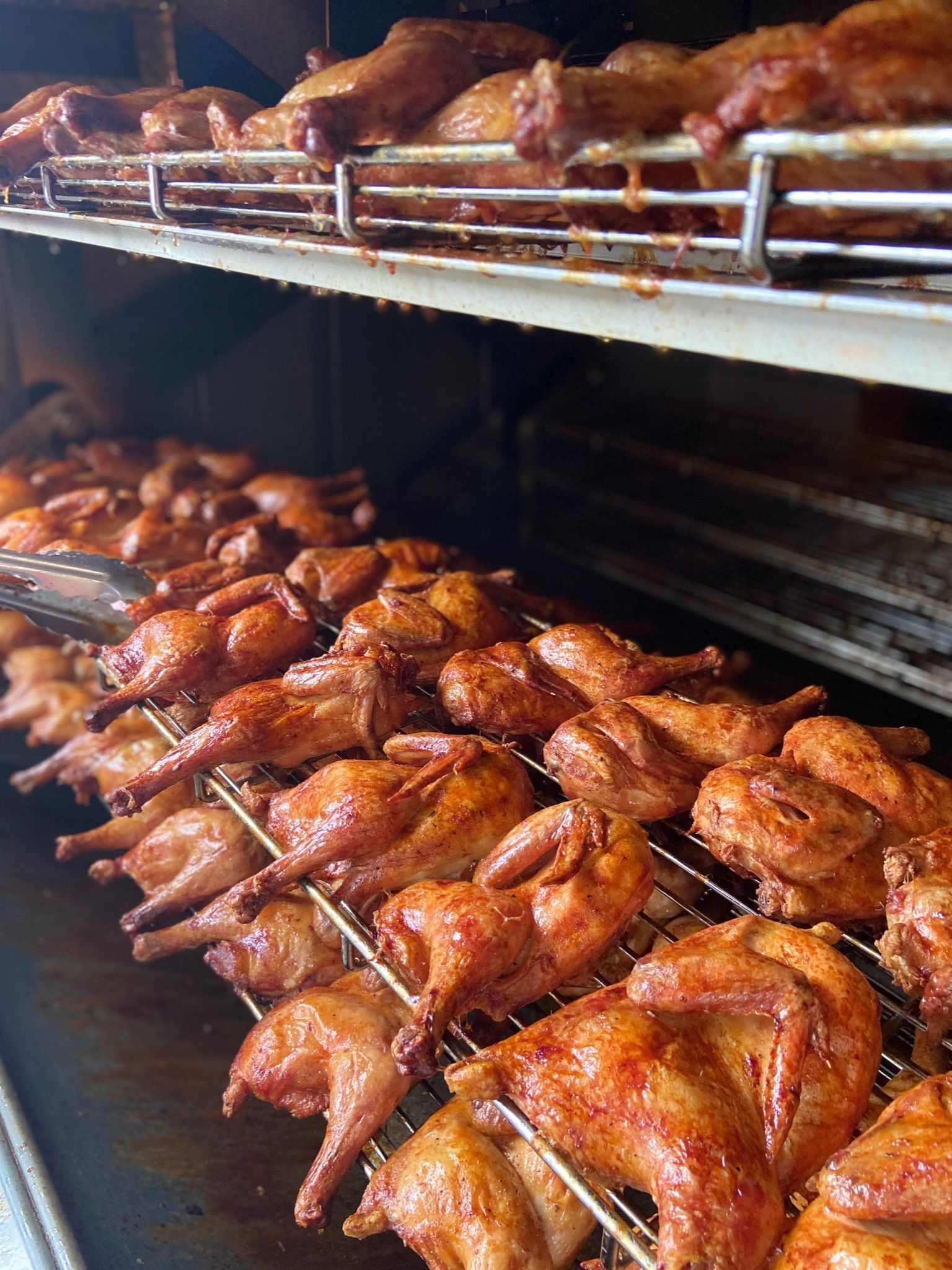 Roasted chickens on racks inside a commercial oven.