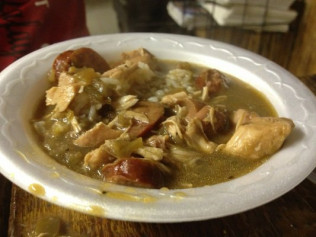 Bowl of gumbo with chicken, sausage, and rice in a white foam bowl.