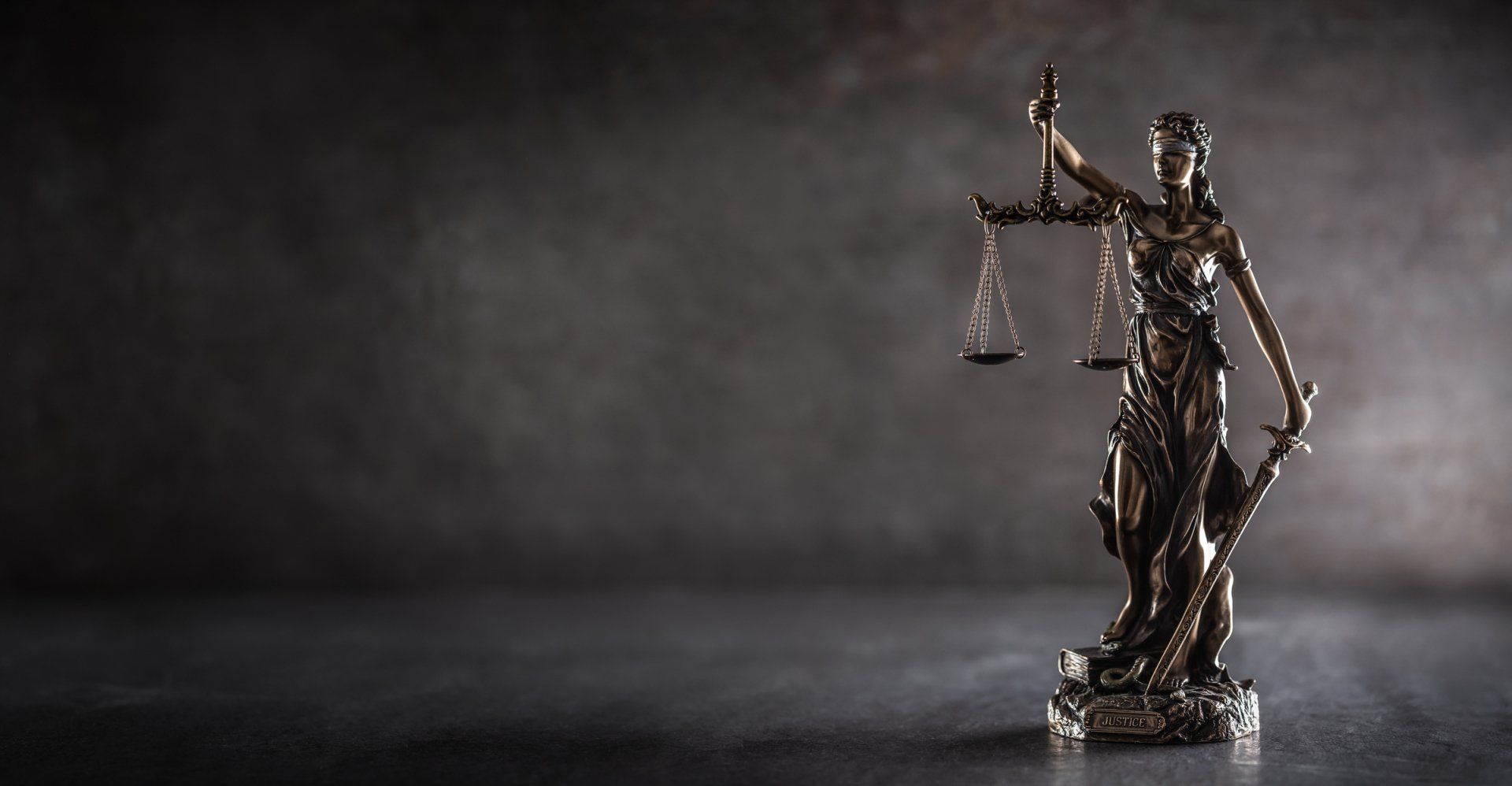 Statue of Lady Justice holding scales, against a dark, moody background. Statue of Lady Justice holding scales, against a dark, moody background.