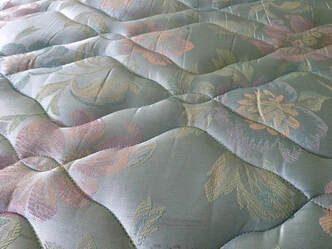 Close-up of a quilted mattress surface with a floral pattern in pastel colors.