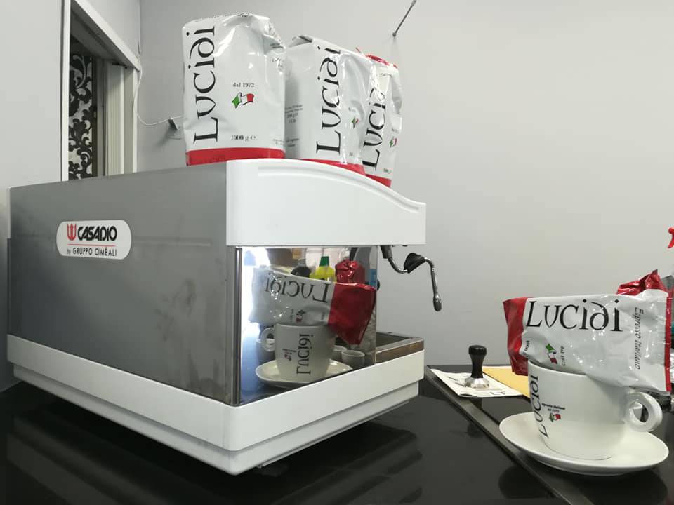 Una macchina da caffè per bar, alcune confezioni di caffè macinato e una tazza Lucidi Espresso Italiano