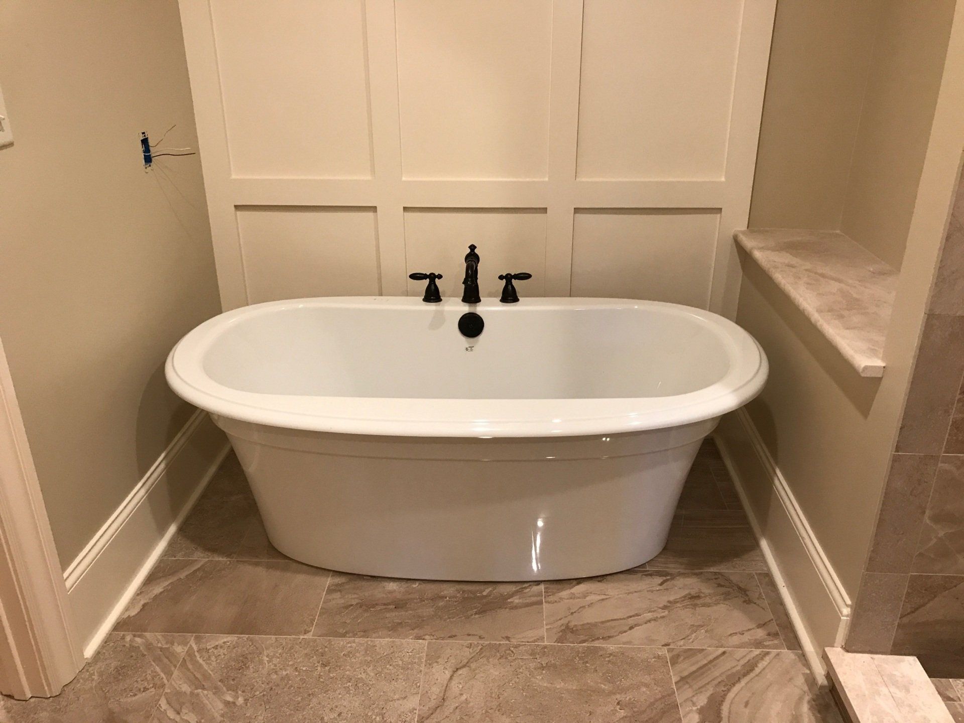 A white bathtub is sitting on a tiled floor in a bathroom.