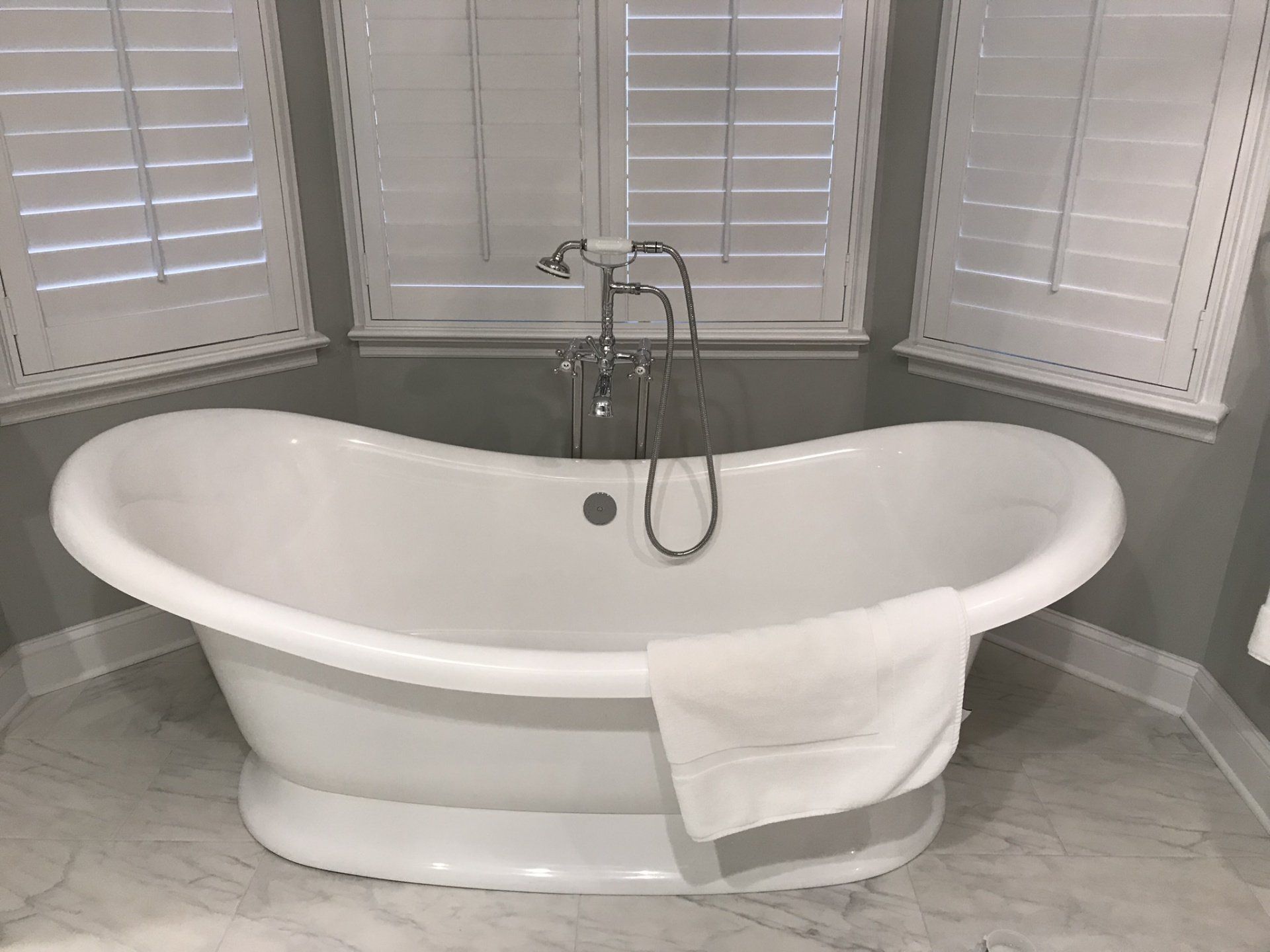 A white bathtub is sitting in a bathroom next to a window.