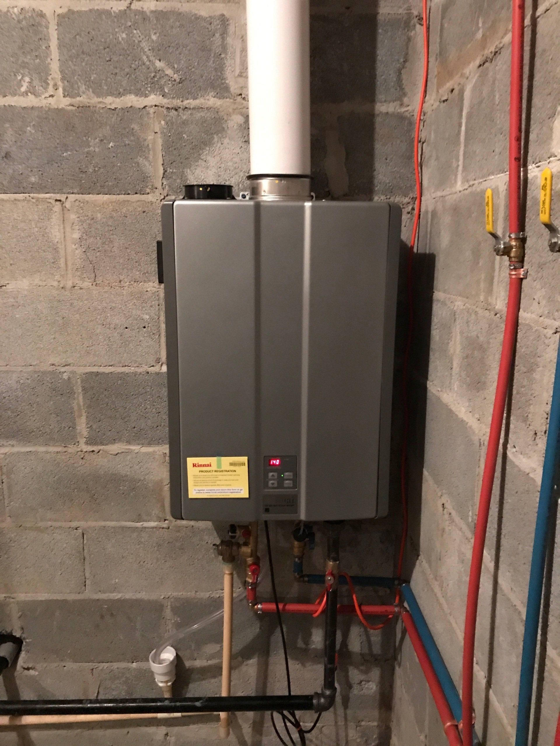 A gray water heater is mounted to a brick wall
