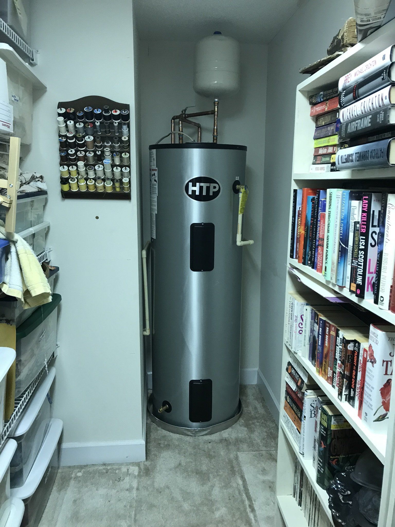 A htp water heater is sitting in a room filled with books.