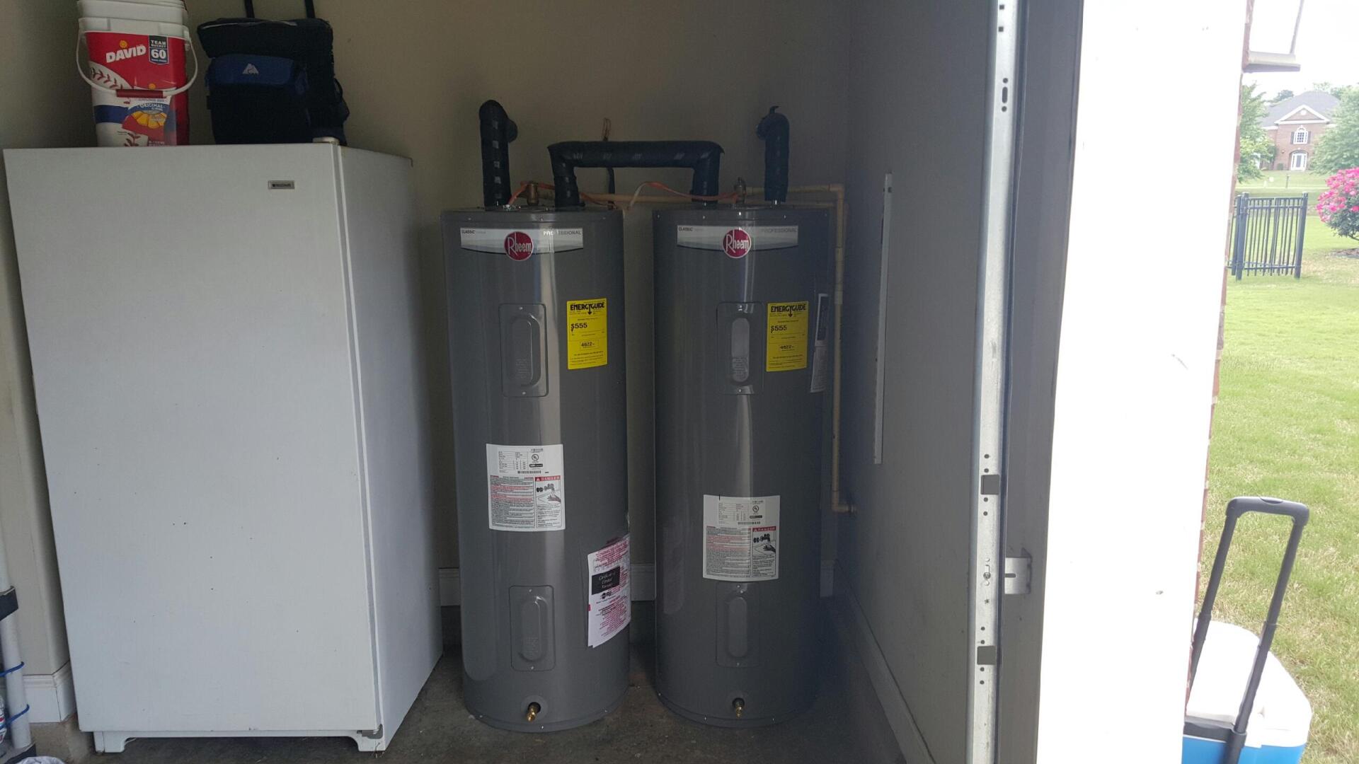 Three water heaters are sitting in a shed next to a refrigerator.