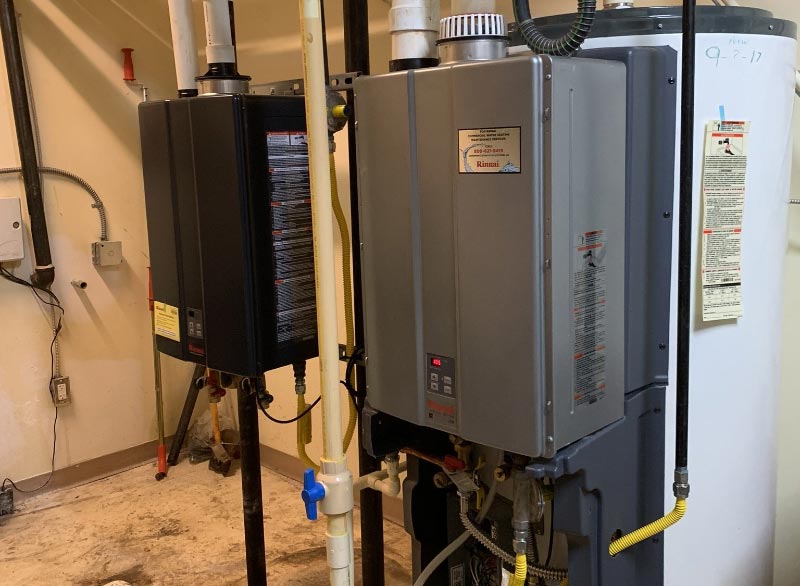 J Henry Plumbing installed tankless  water heaters that are sitting next to each other in a room .