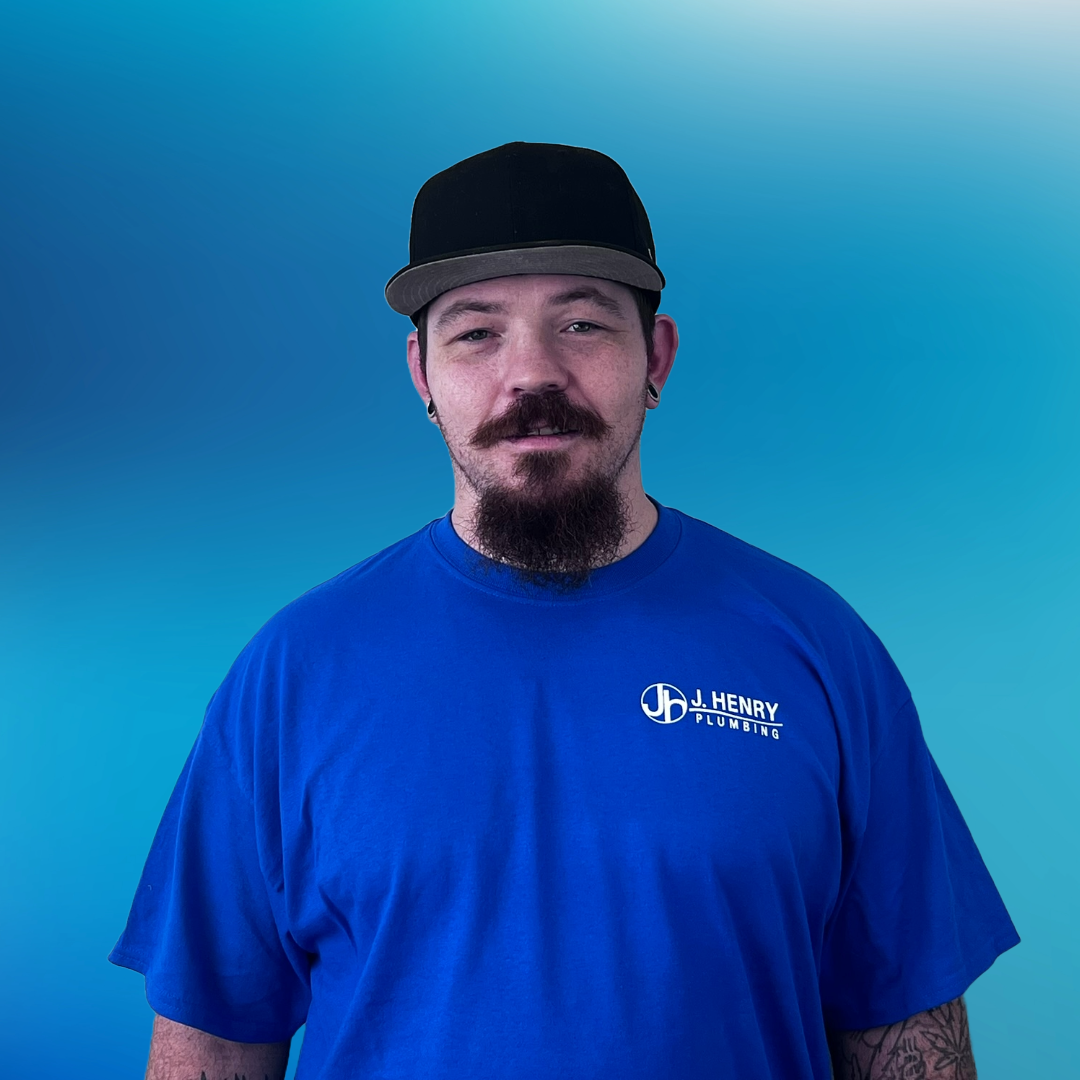 A man wearing a green shirt and a black hat is standing in front of a blue background.