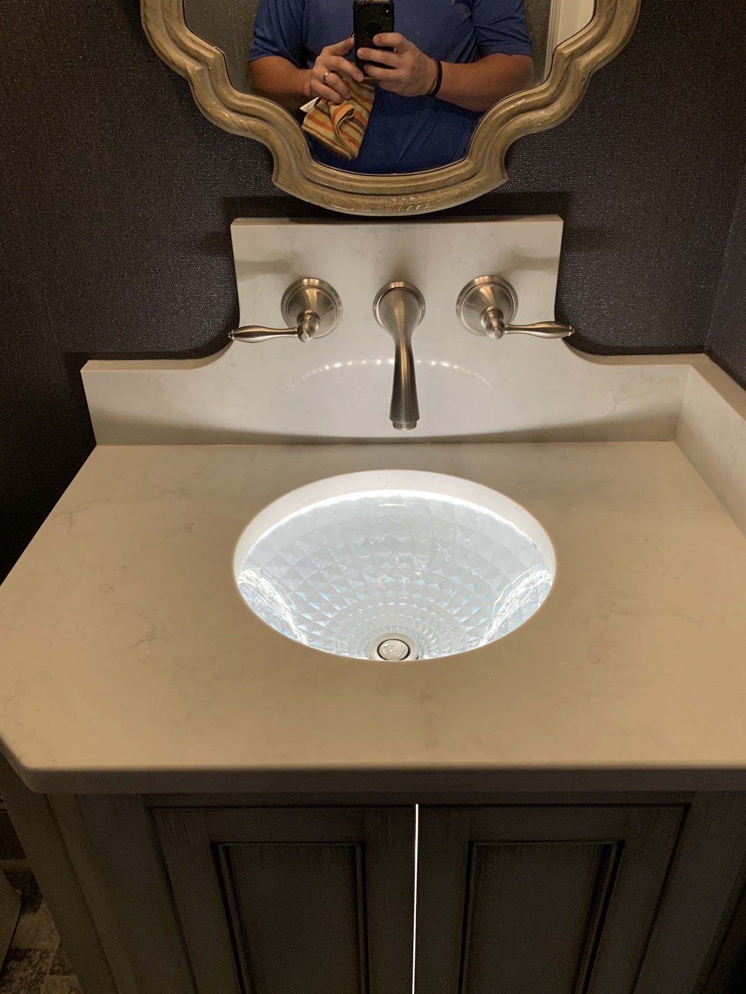 A man is taking a picture of himself in a bathroom sink.