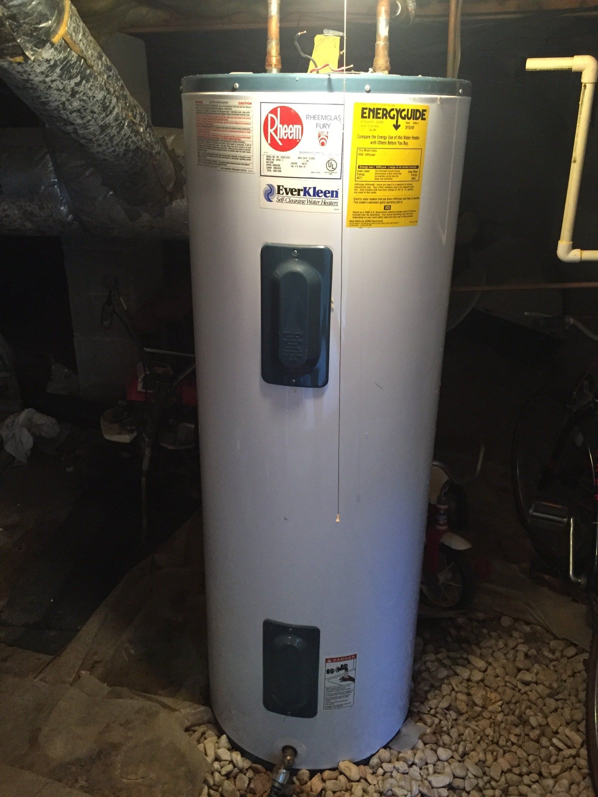 A white water heater is sitting in a basement.