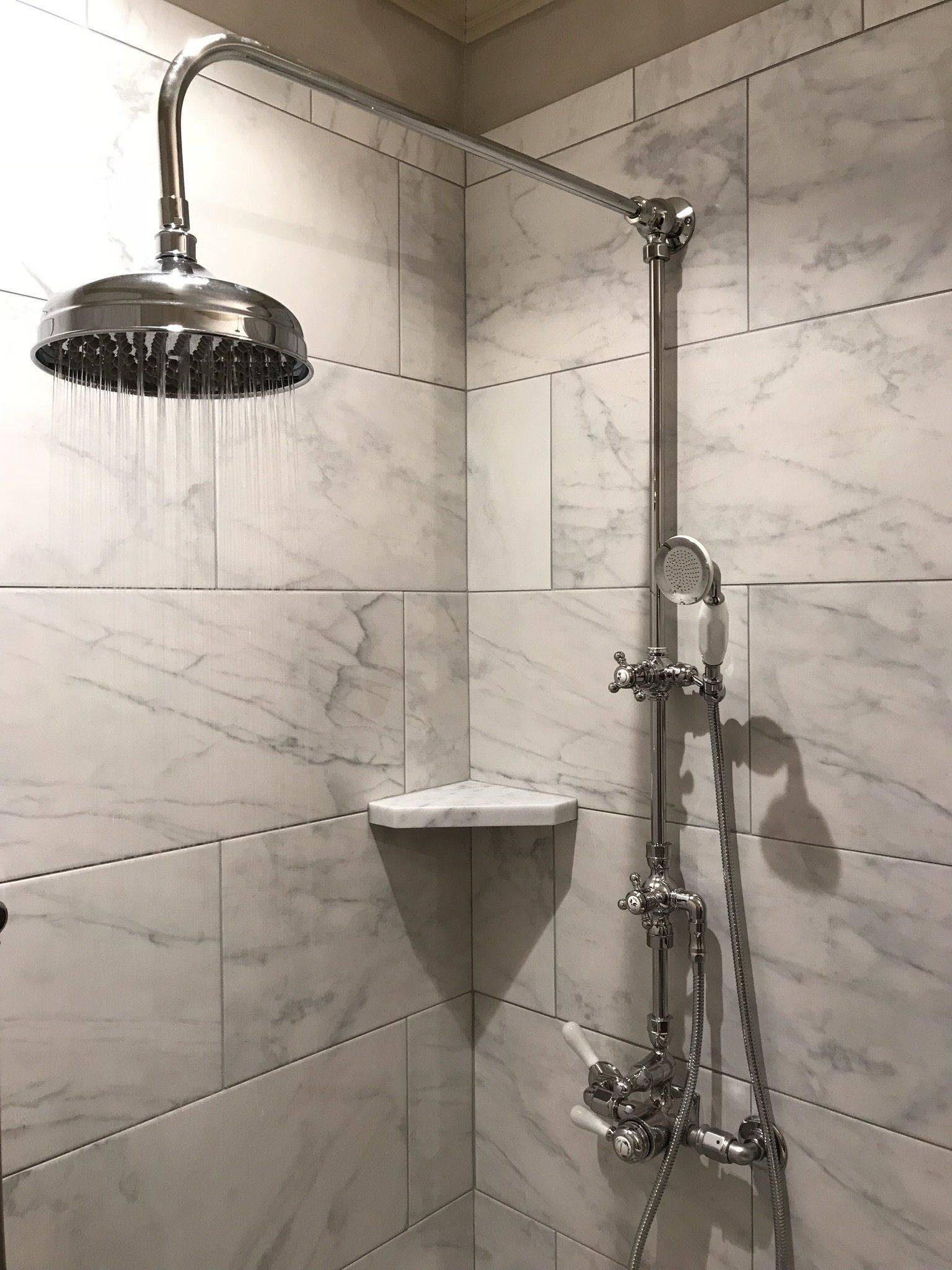 A shower head is hanging from the ceiling in a bathroom.