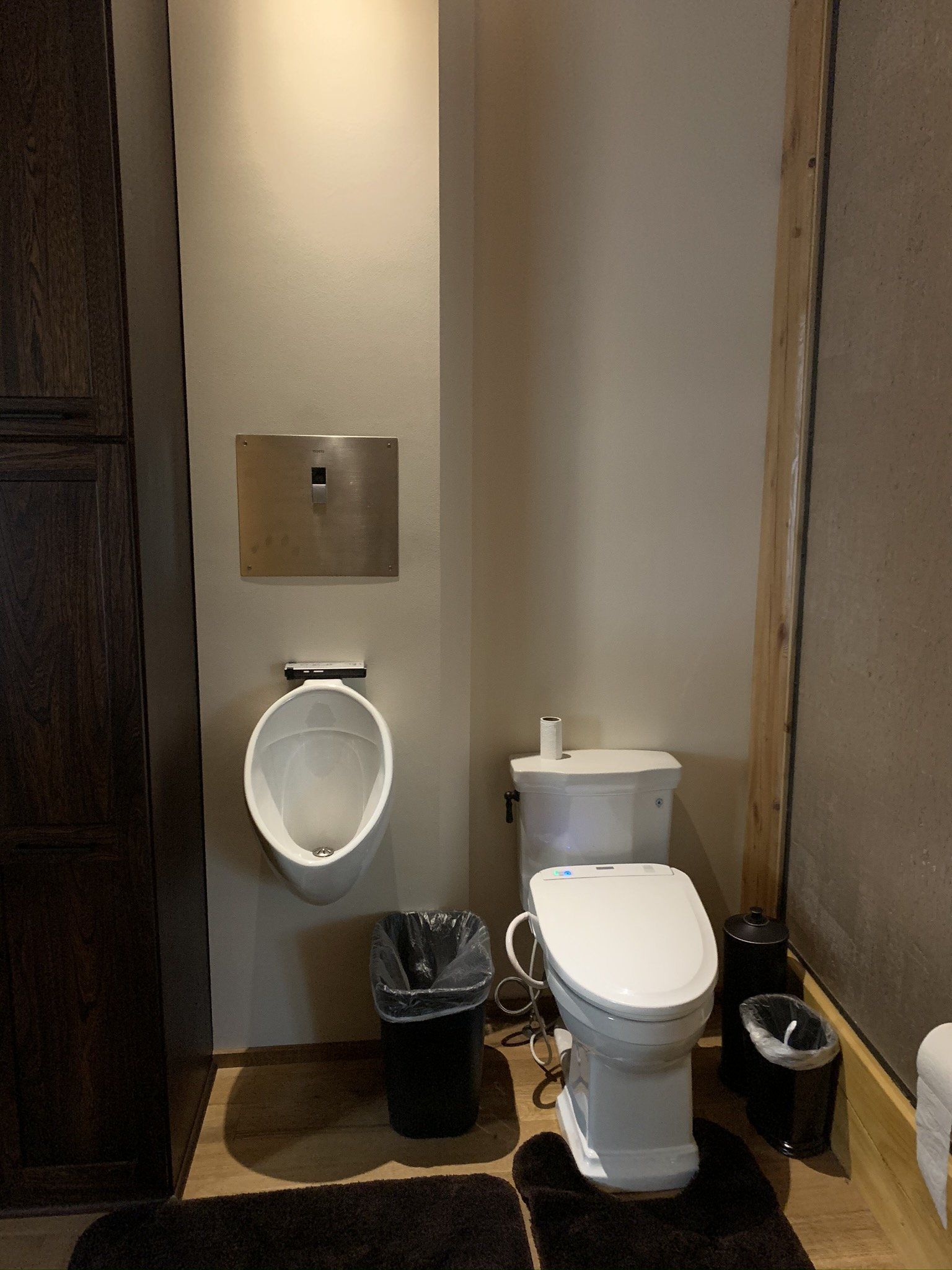 A bathroom with a toilet , urinal and trash can.
