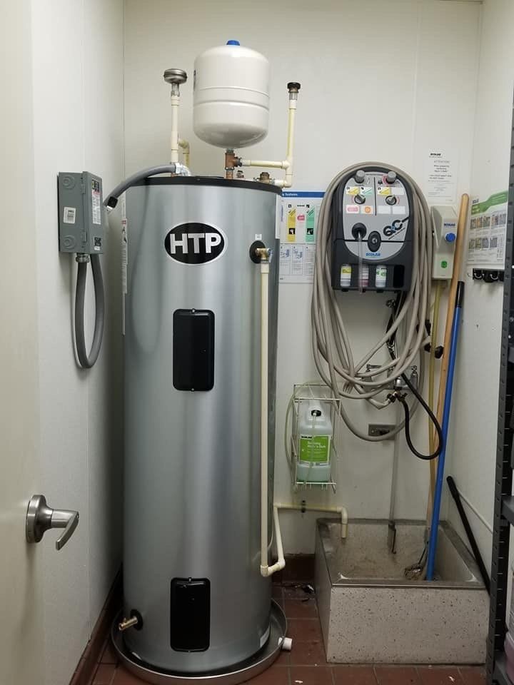 A htp water heater is sitting in a room next to a wall.