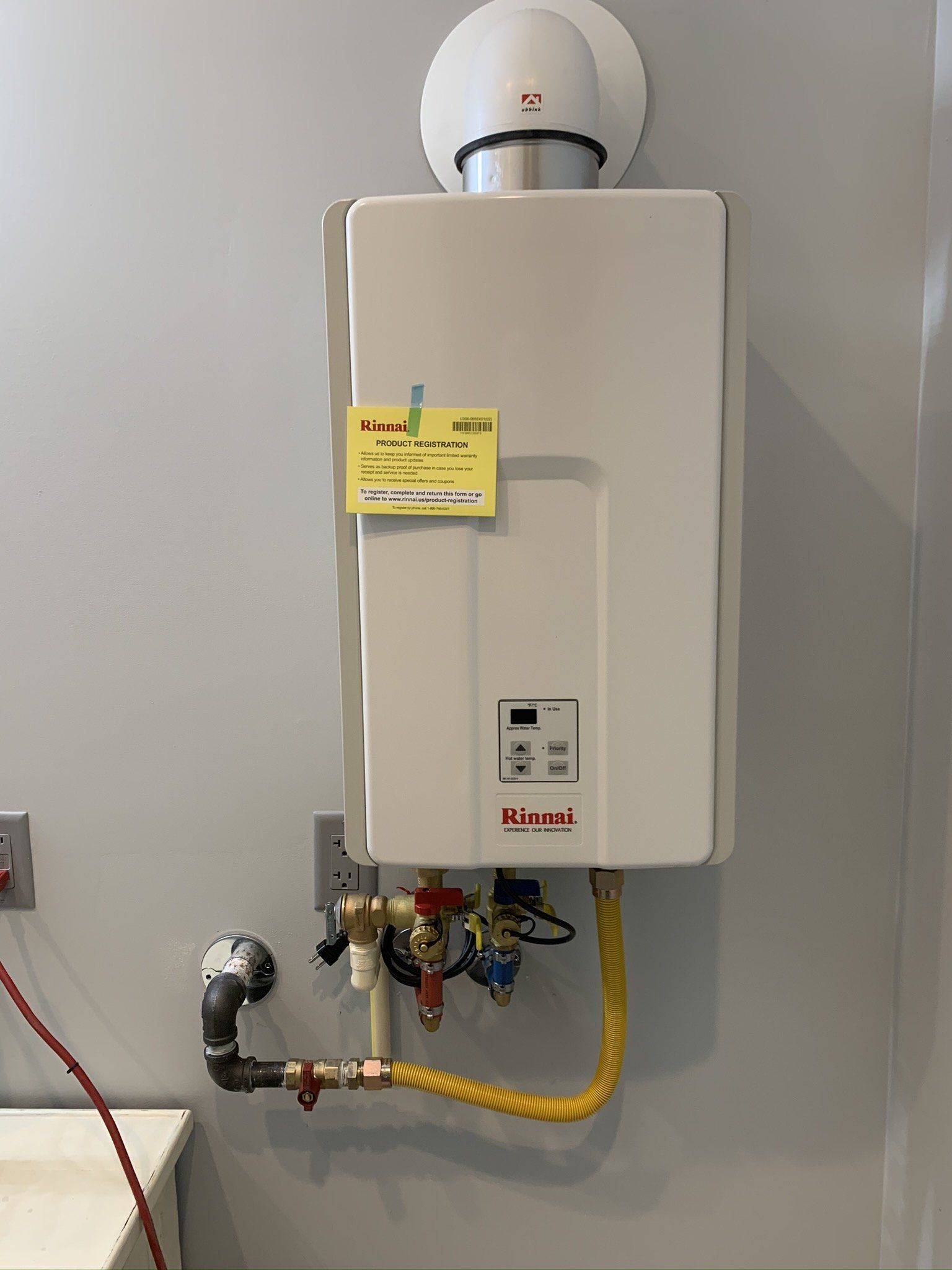 A white water heater is hanging on a wall next to a sink.