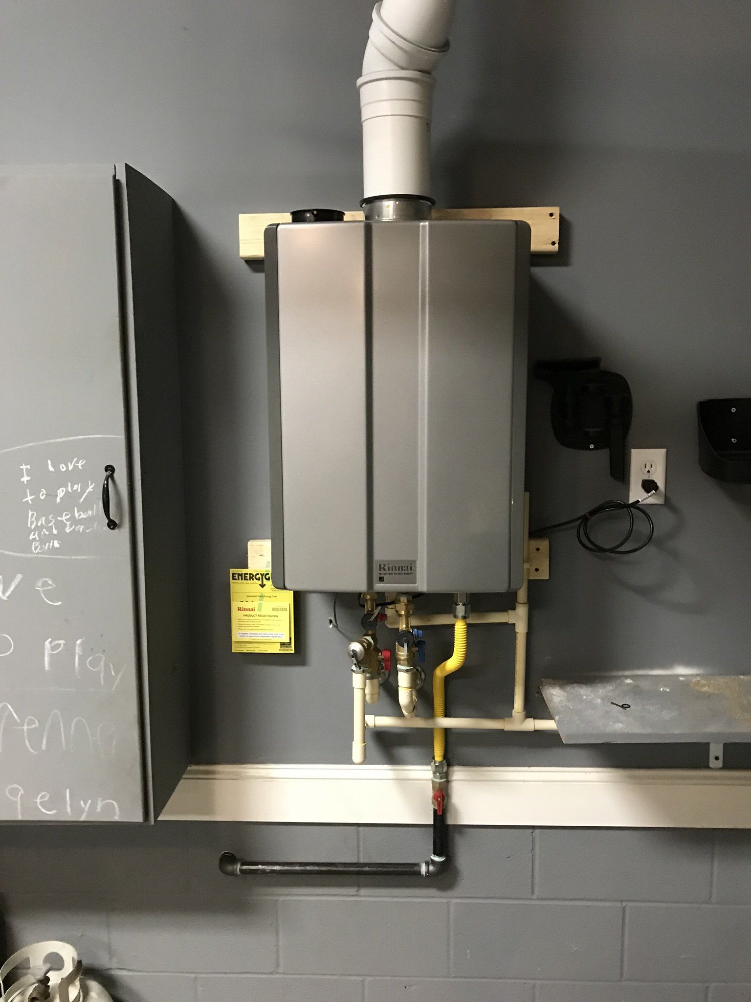 A water heater is hanging on a wall in a garage.