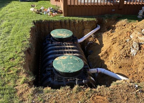 J Henry Plumbing is installing a septic tank that is being installed in a hole in the ground .