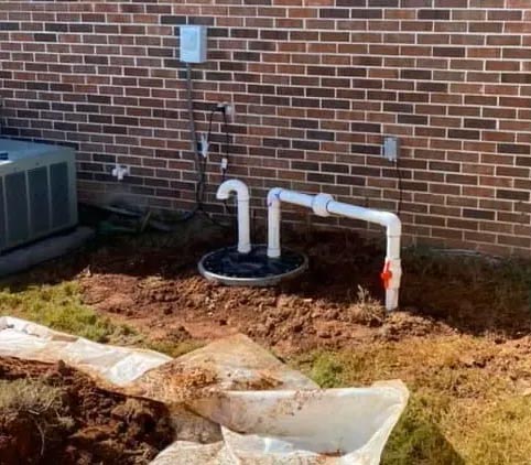 a sump pump is being installed in the backyard of a brick house .