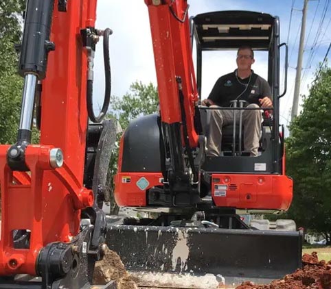 J Henry Plumbing is driving a red and black excavator .