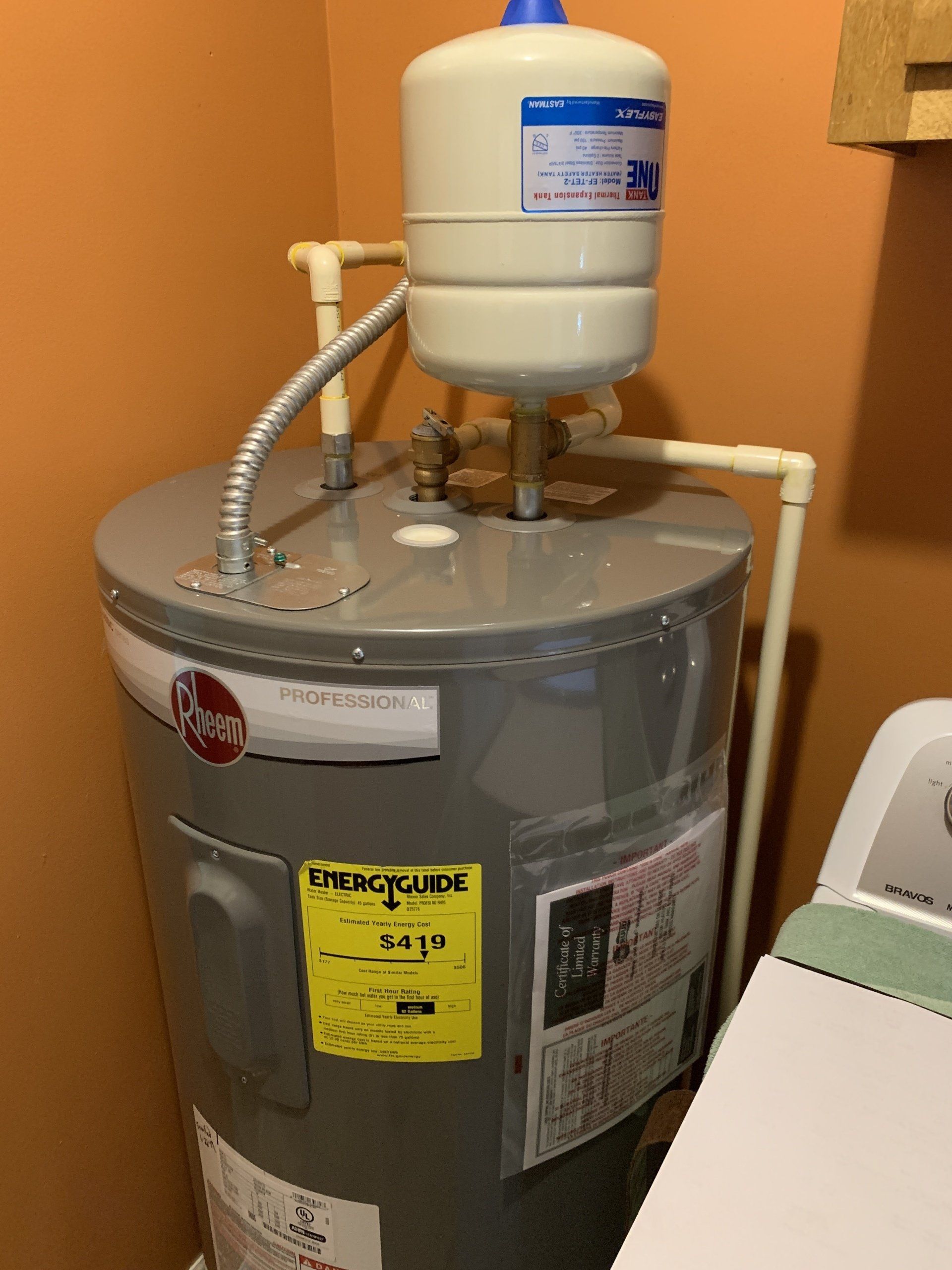A water heater is sitting next to a washer and dryer in a room.