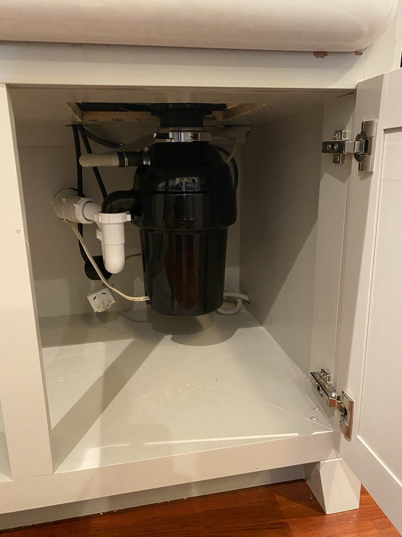 A garbage disposal is sitting under a sink in a cabinet.
