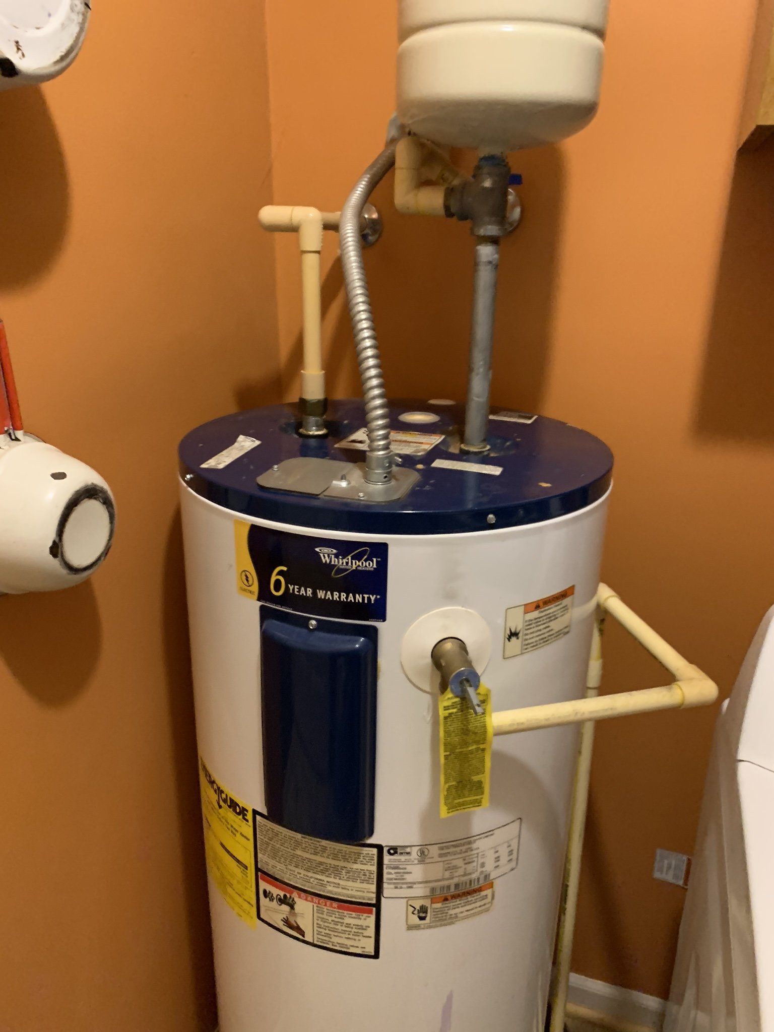 A water heater is sitting in a bathroom next to a sink.