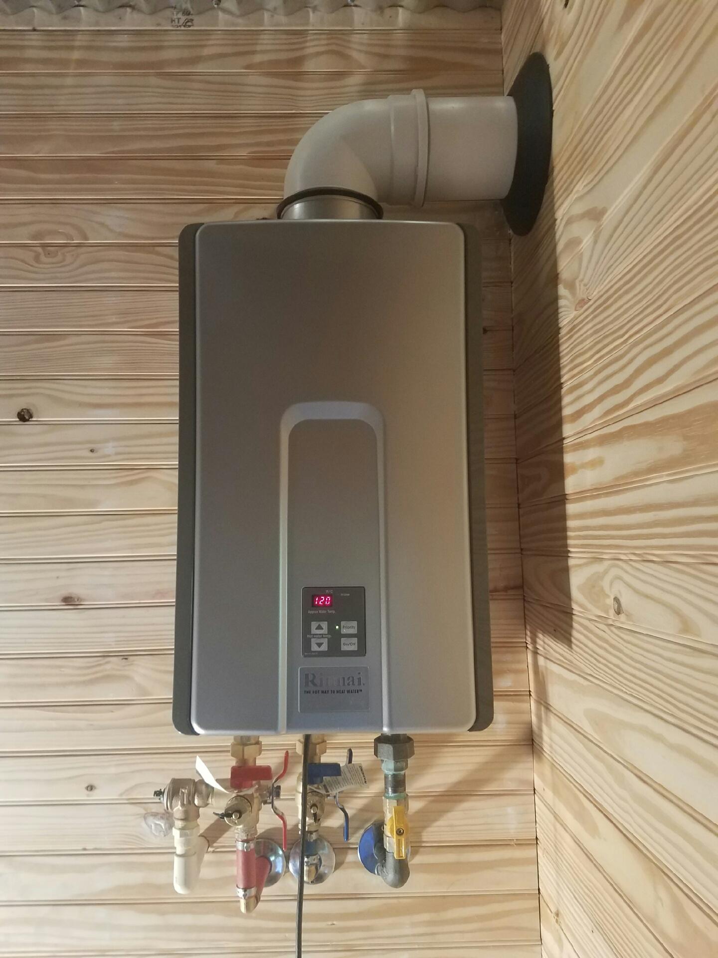 A stainless steel water heater is mounted to a wooden wall.