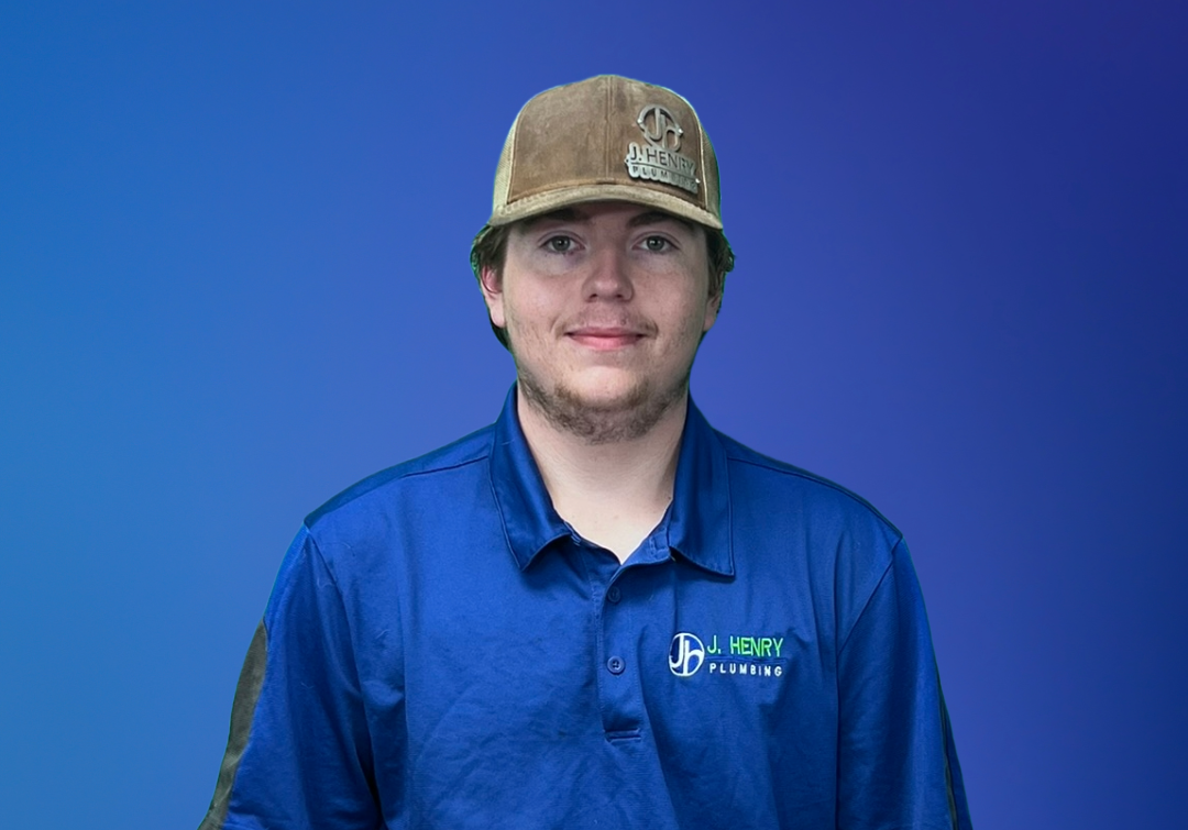 A young man wearing a hat and a blue shirt is standing in front of a blue background.