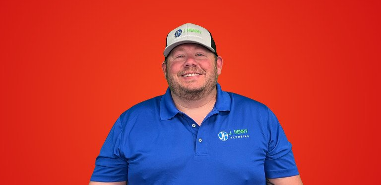 A man wearing a blue shirt and a white hat is smiling.
