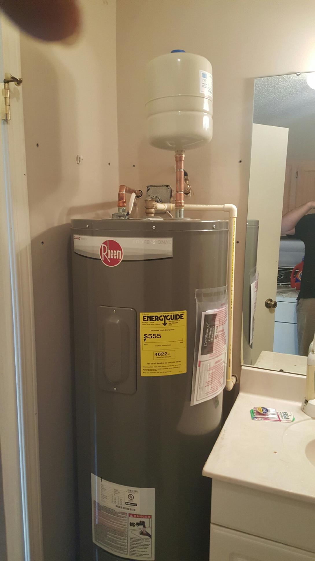 A water heater is sitting in a bathroom next to a sink.