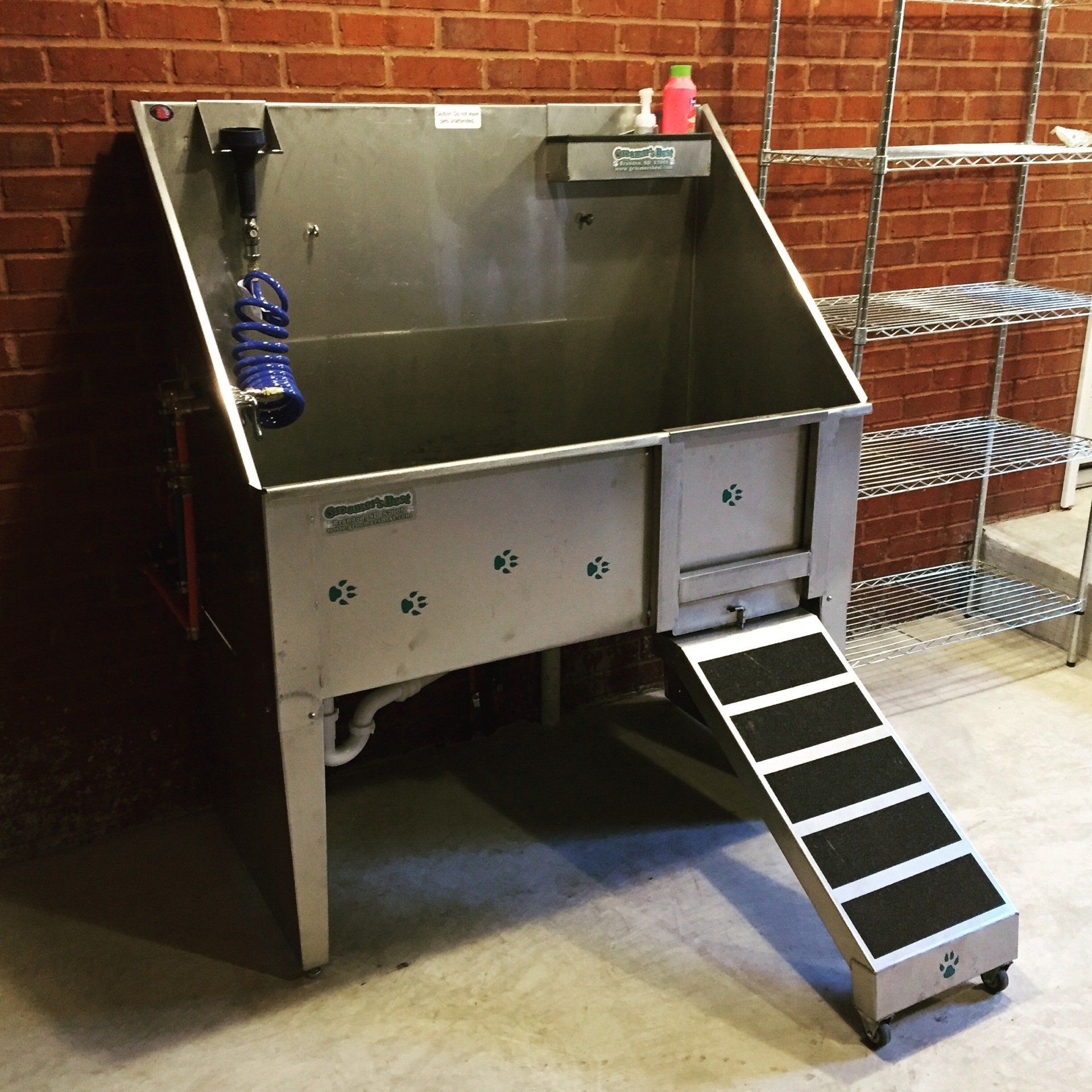 A stainless steel dog bath tub with stairs leading up to it