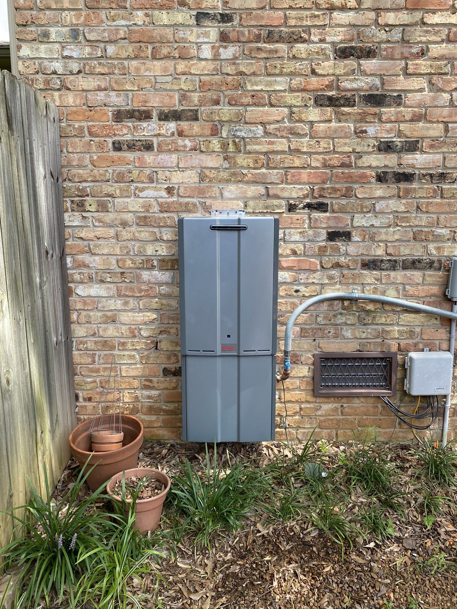 A Tankless water heaters iinstalled on the side of a brick buildin