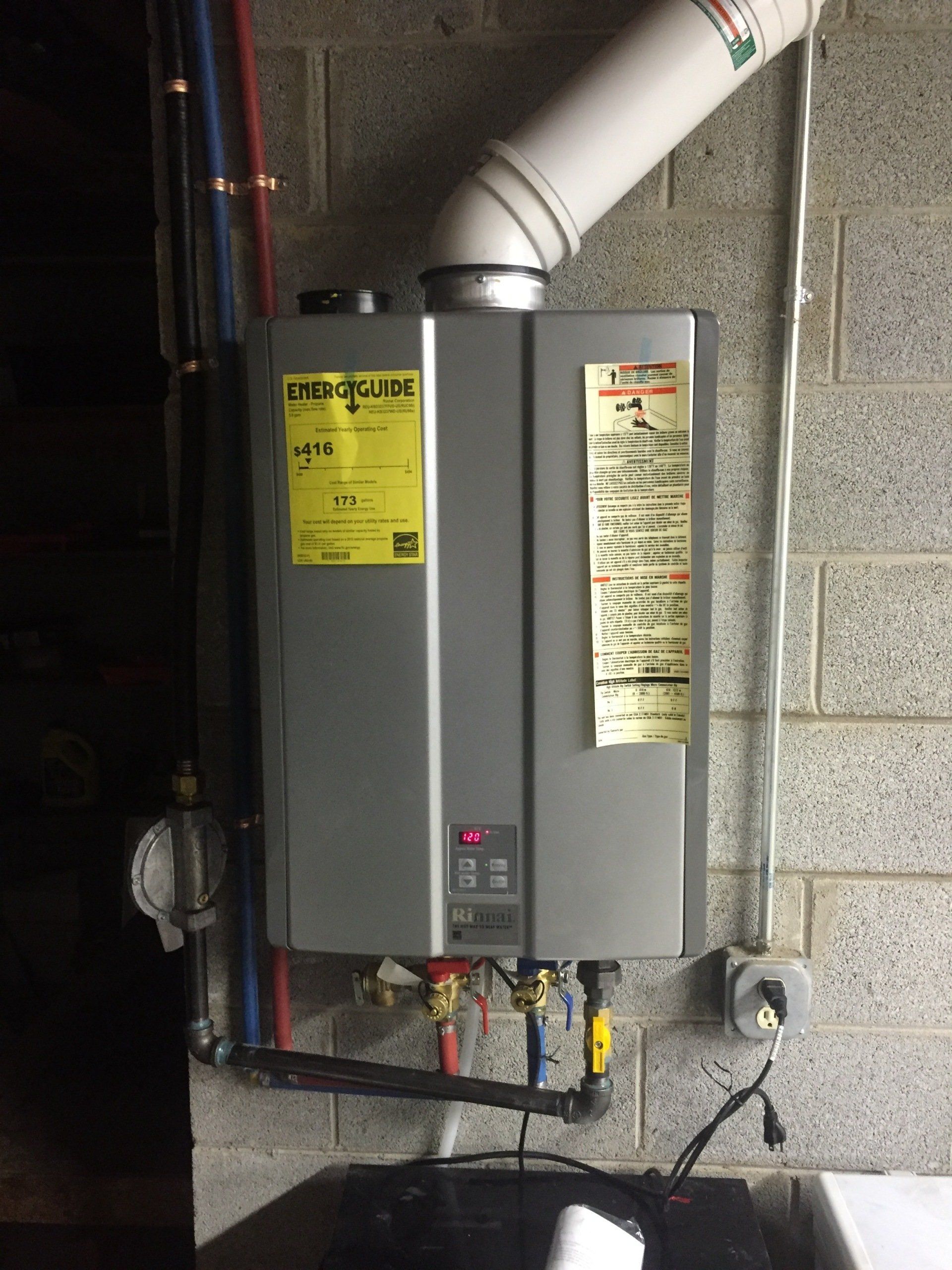 A water heater is hanging on a brick wall.