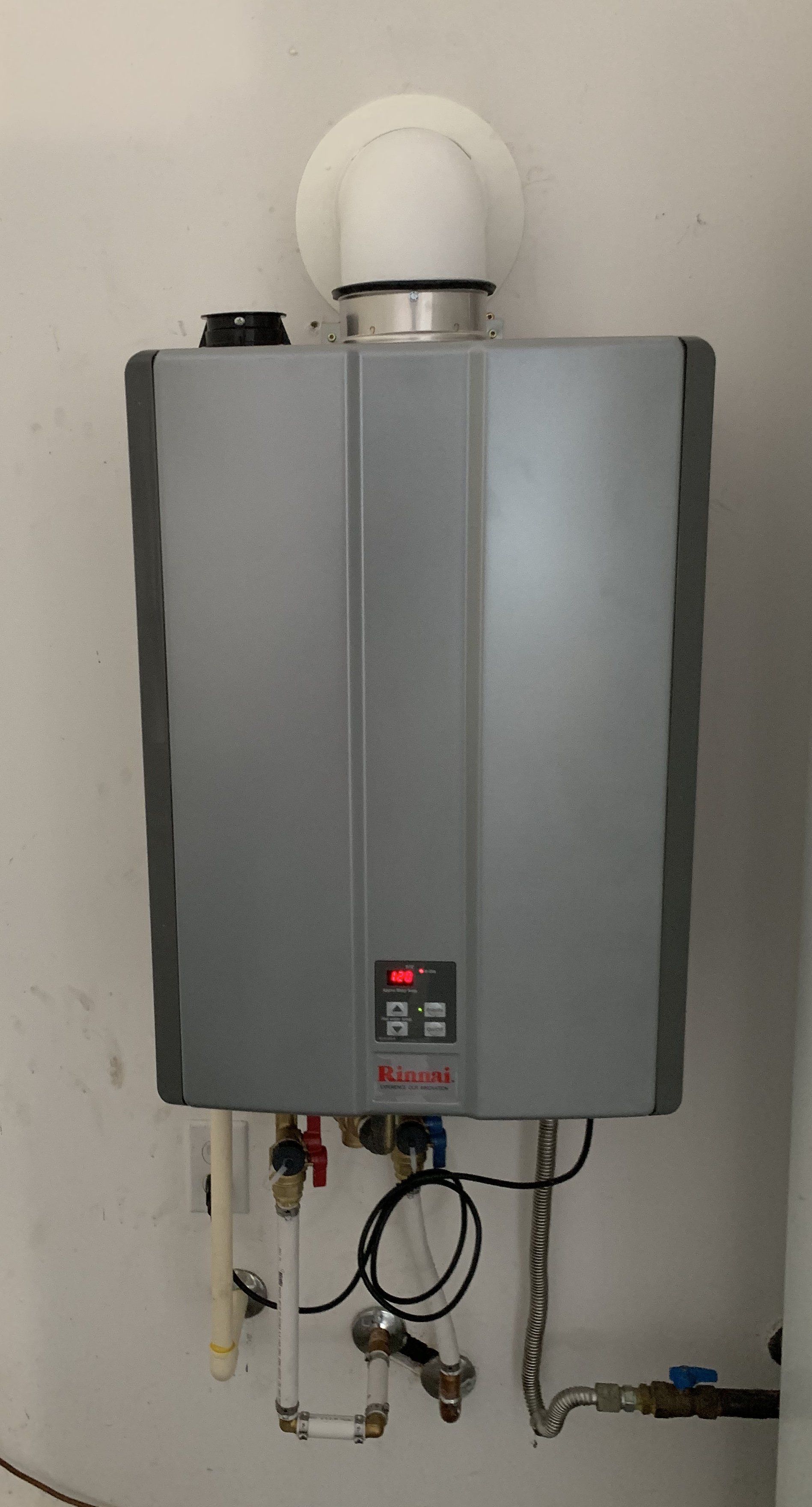 A gray water heater is hanging on a white wall.