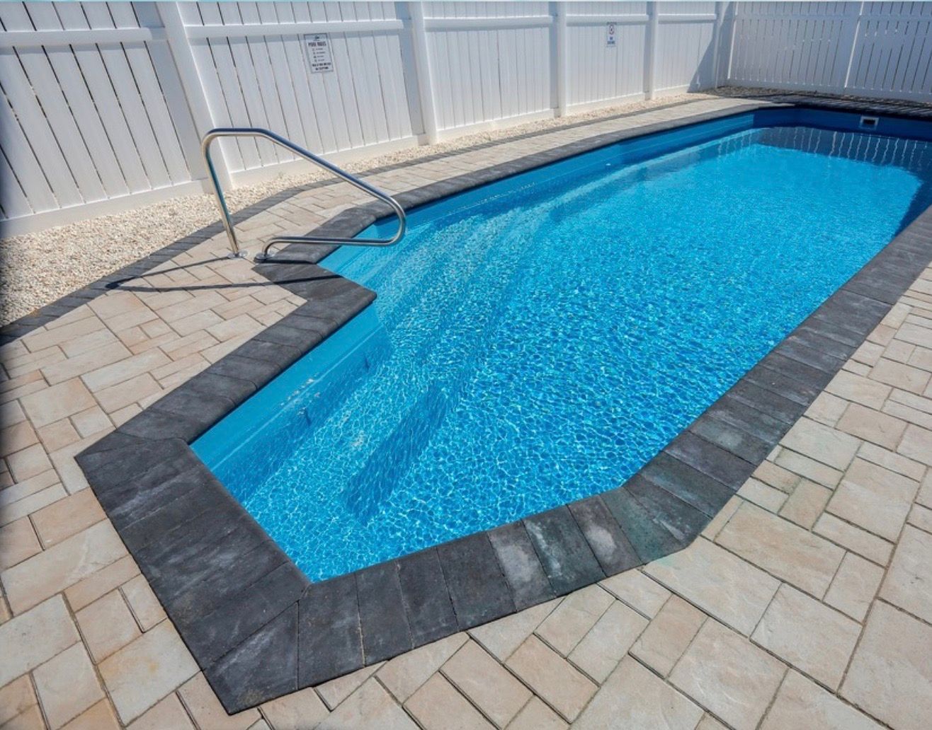 A swimming pool with a white fence in the background