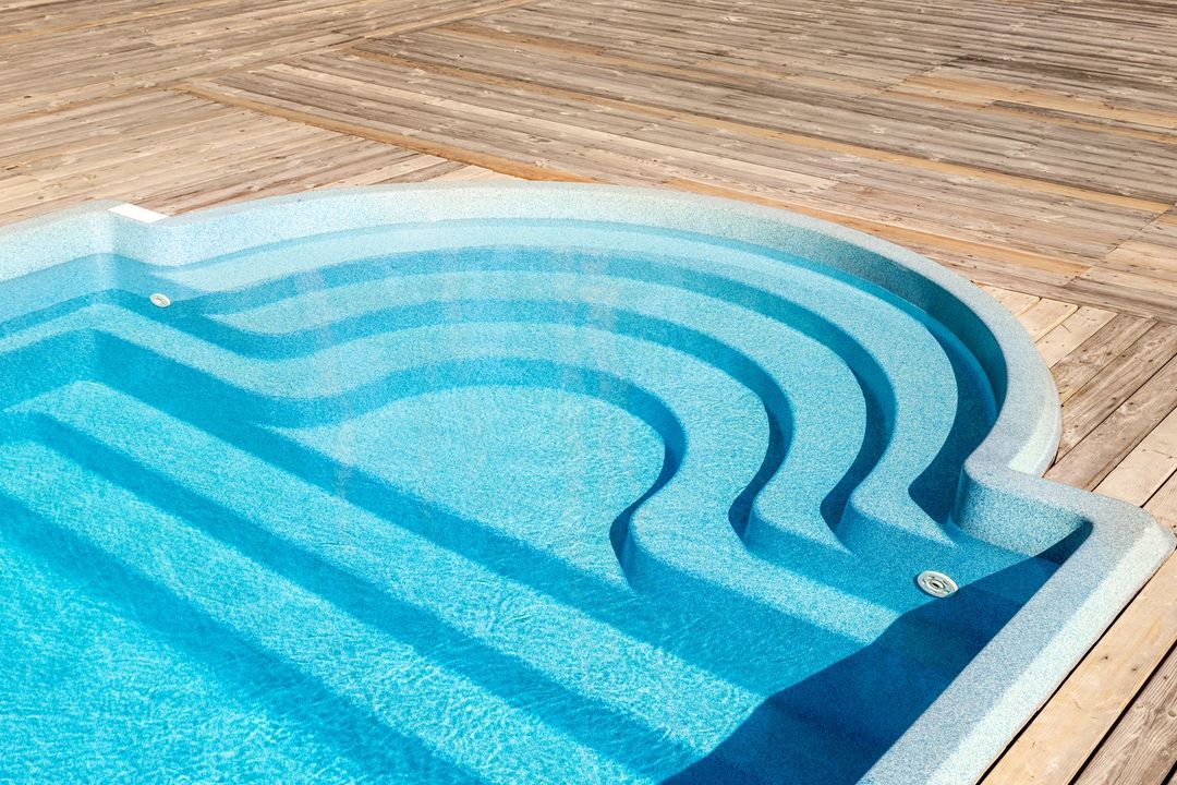A swimming pool with stairs leading up to it on a wooden deck.