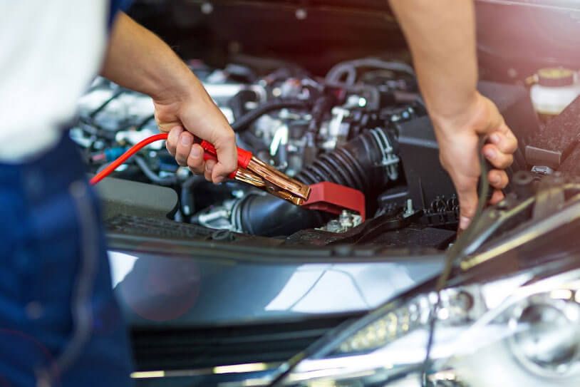 A man is charging a car battery with a jump starter.