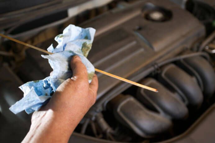 A person is checking the oil level of a car with a dipstick.