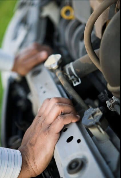A man is working on a car with the hood open.